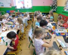 Widok ogólny na salę z dziećmi malującymi koniki.