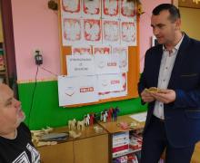 Dwóch mężczyzn, ten po prawej stronie trzyma aniołka w dłoniach