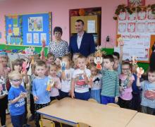Zdjęcie grupowe dzieci z pracami w rękach - w tle nauczyciele i opiekunowie