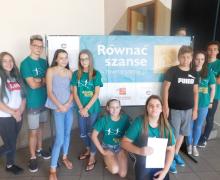 Młodzież z plakatem "Równać szanse" w tle