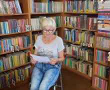 Kobieta siedząca w bibliotece z regałem w tle