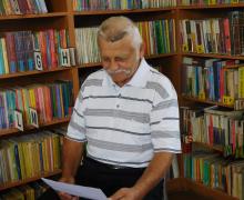 Mężczyzna z wąsem siedzący w bibliotece