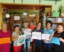 Grupa seniorów trzymających afisze w bibliotece